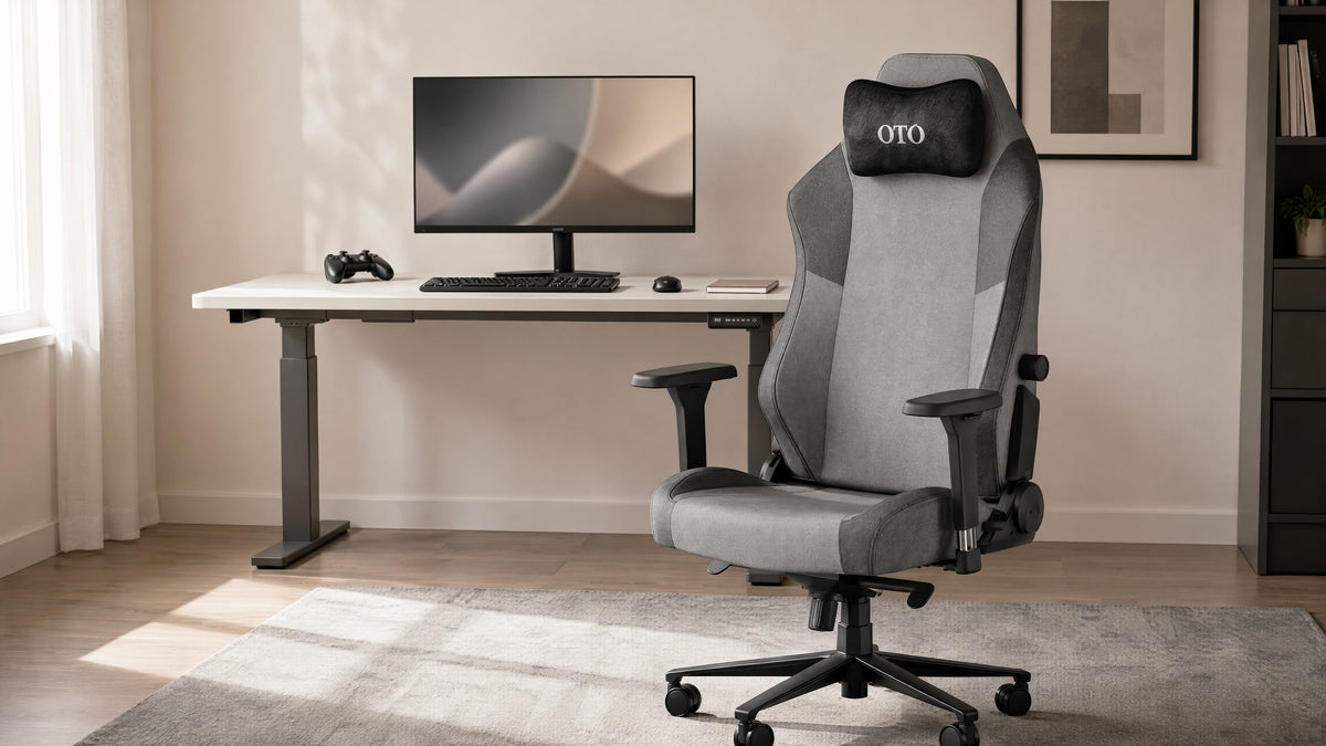An OTO fabric gaming chair in a bright home office with a height-adjustable desk, monitor and game controller.